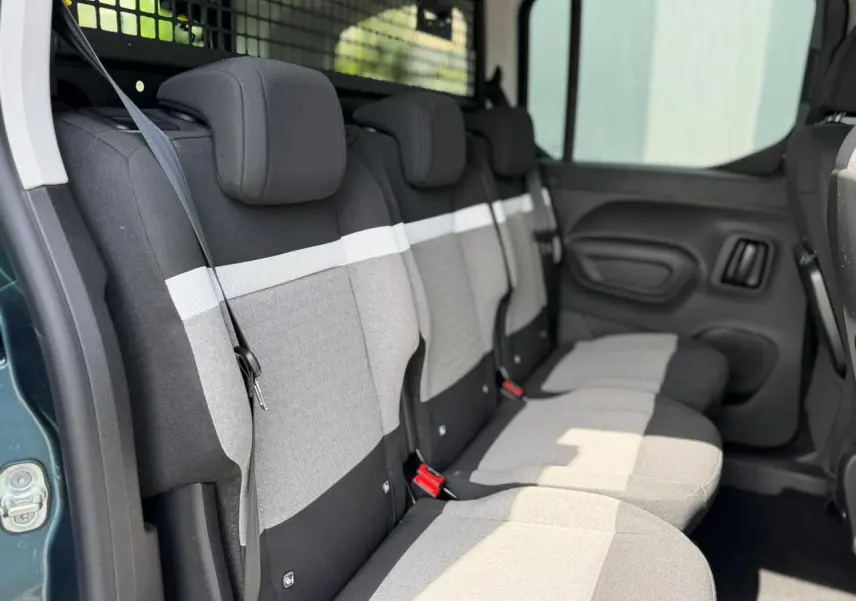 Vue latérale intérieure des trois sièges arrière gris et noirs du Citroën Berlingo Multispace avec ceinture et porte coulissante ouverte.