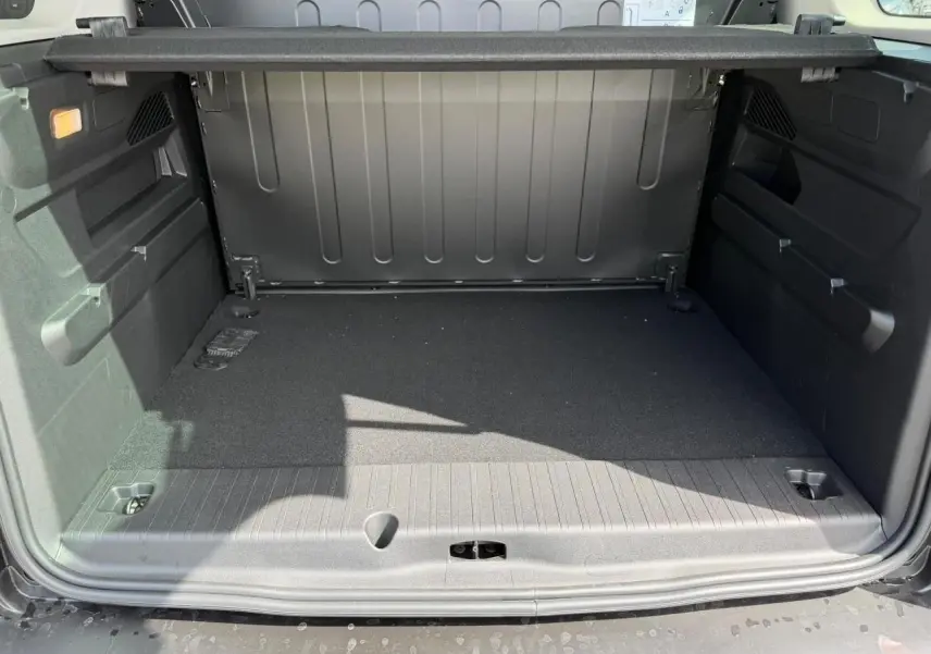 Coffre ouvert vu de l'arrière du Citroën Berlingo Multispace bleu Kiama, espace de chargement vide et tapis noir.
