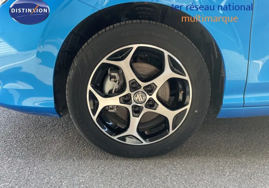 Gros plan sur la roue avant droite d'une MG3 2024 bleu Como Metal avec jante alliage bicolore et logo MG au centre.