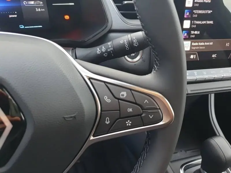 Gros plan sur le volant multifonction et la commande d’essuie-glace du Renault Captur gris Cassiopée, tableau de bord partiellement visible.