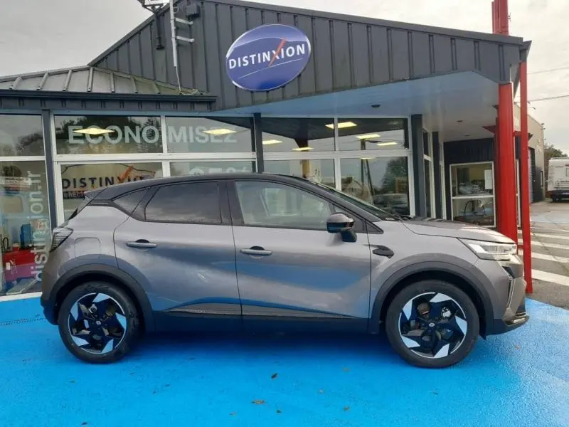 Renault Captur 1.6 E-Tech gris Cassiopée en profil droit, avec jantes alu noires et toit noir contrasté.
