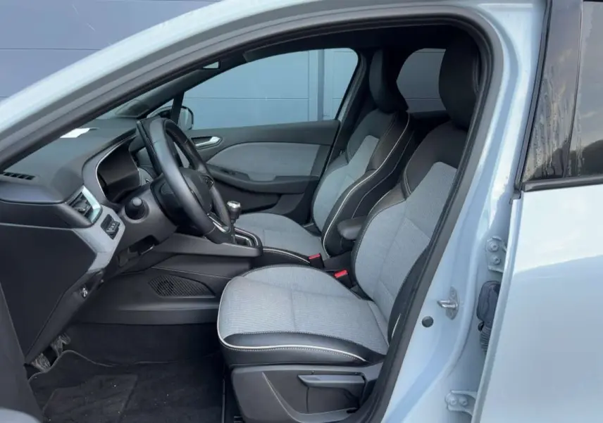 Vue intérieure côté conducteur de la Renault Clio 2025 gris rafale, sièges bi-matière et volant cuir multifonctions.