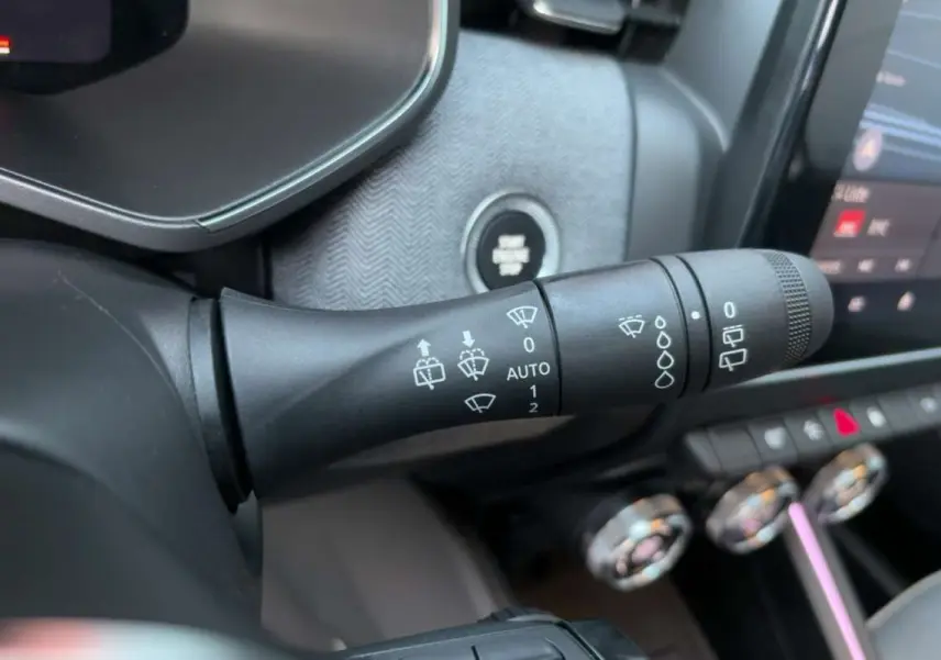Gros plan sur la commande d’essuie-glace de la Renault Clio 2025, avec tableau de bord et bouton start/stop visibles.
