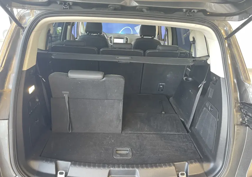 Vue arrière du coffre ouvert du Ford S-MAX Vignale gris magnetic 2022, montrant les sièges arrière partiellement rabattus.