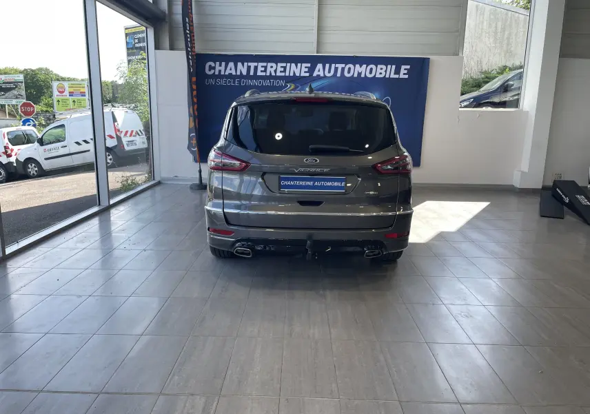 Vue arrière du Ford S-MAX Vignale 2022 gris magnetic, avec double sortie d'échappement et logo Vignale visible en showroom.