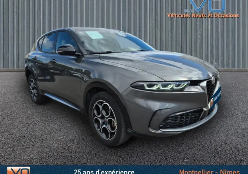 Vue 3/4 avant d'une Alfa Romeo Tonale gris métallisé avec jantes alliage 18 pouces et phares LED allumés.