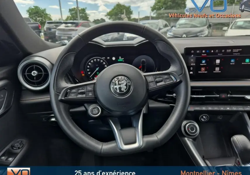 Vue centrée sur le volant sport de l'Alfa Romeo Tonale gris 2023 avec tableau de bord digital et écran tactile.