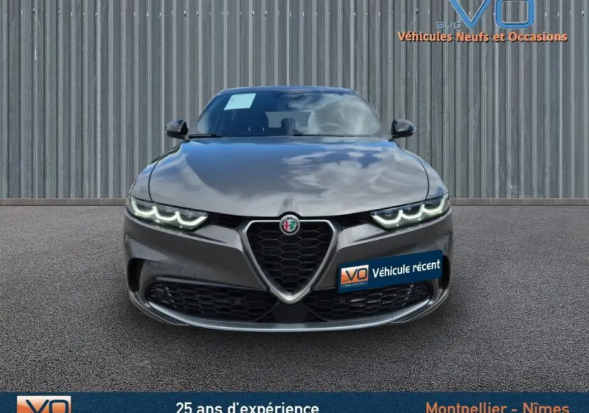 Vue frontale d'une Alfa Romeo Tonale gris métallisé 2023 avec feux LED allumés et calandre caractéristique en V.