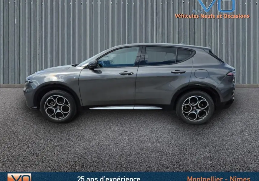 Profil latéral droit d'une Alfa Romeo Tonale gris métallisé 2023 avec jantes alliage 18 pouces sur fond urbain.