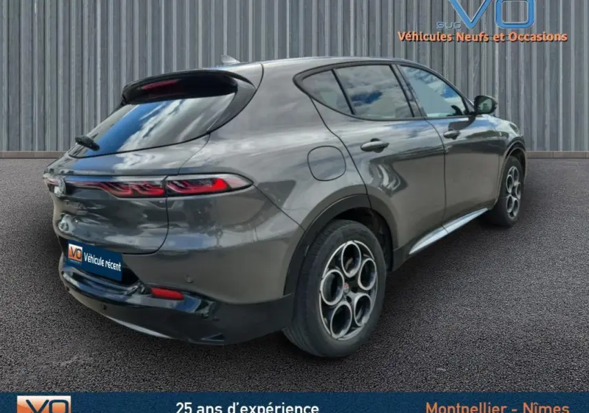 Vue 3/4 arrière droite d'une Alfa Romeo Tonale grise 2023 avec jantes alliage 18 pouces et feux arrière allumés