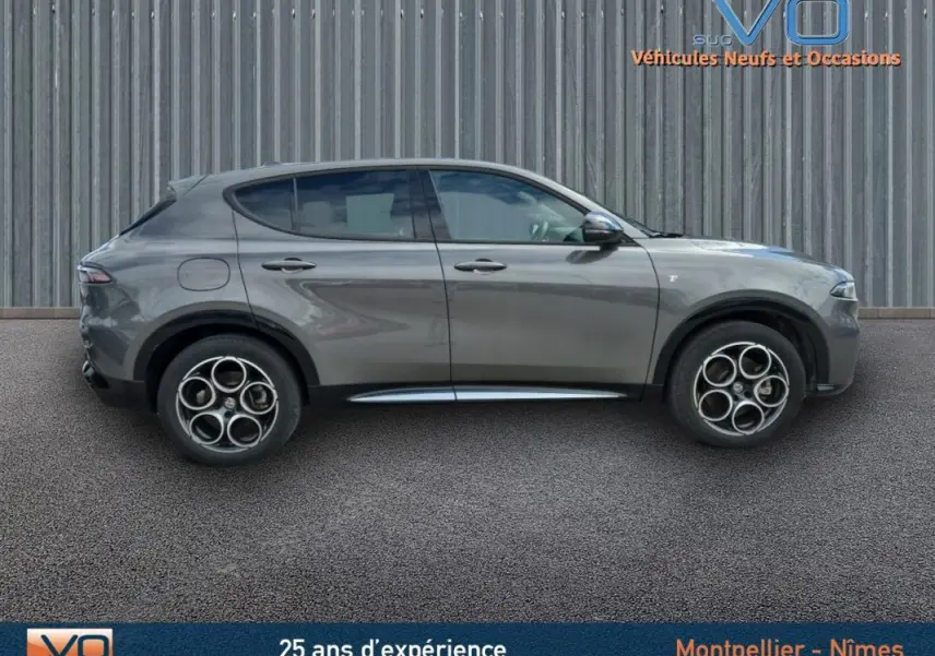Profil latéral droit de l'Alfa Romeo Tonale gris 2023 avec jantes alliage 18 pouces et lignes épurées du SUV hybride rechargeable.