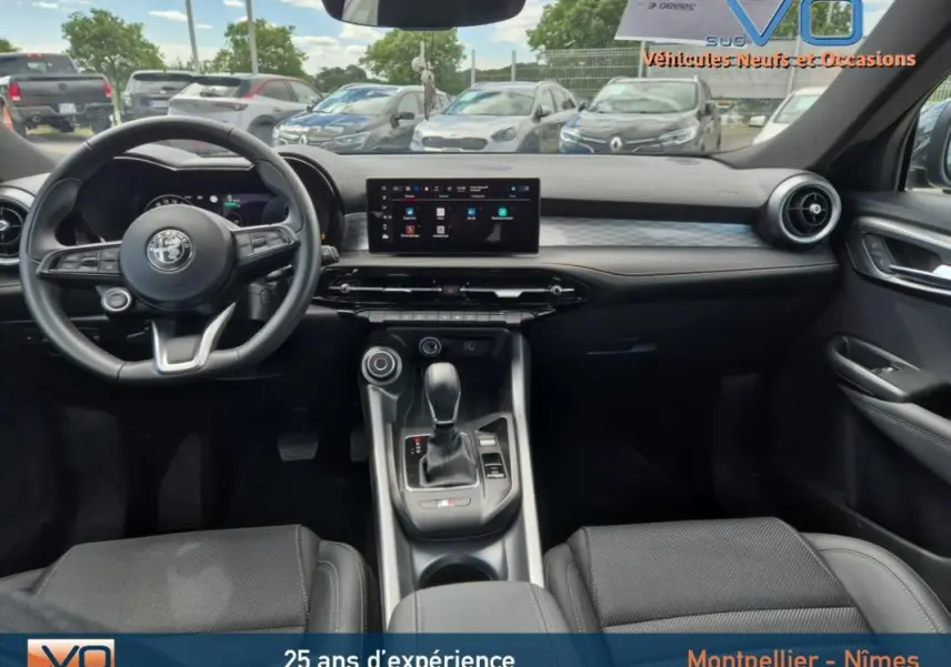 Intérieur de l'Alfa Romeo Tonale 2023 en vue frontale, volant sport noir et écran tactile central moderne.