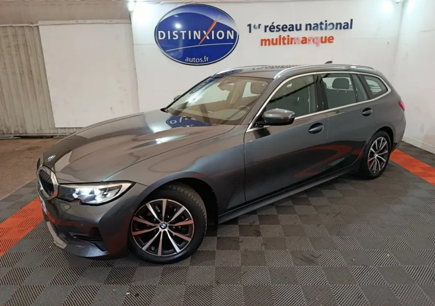 BMW Série 3 316d gris clair vue 3/4 avant droit, avec jantes alliage et phares LED allumés en intérieur showroom.