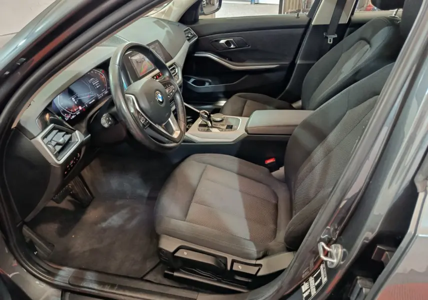 Intérieur avant droit d'une BMW Série 3 gris clair, avec tableau de bord numérique et volant cuir multifonctions.