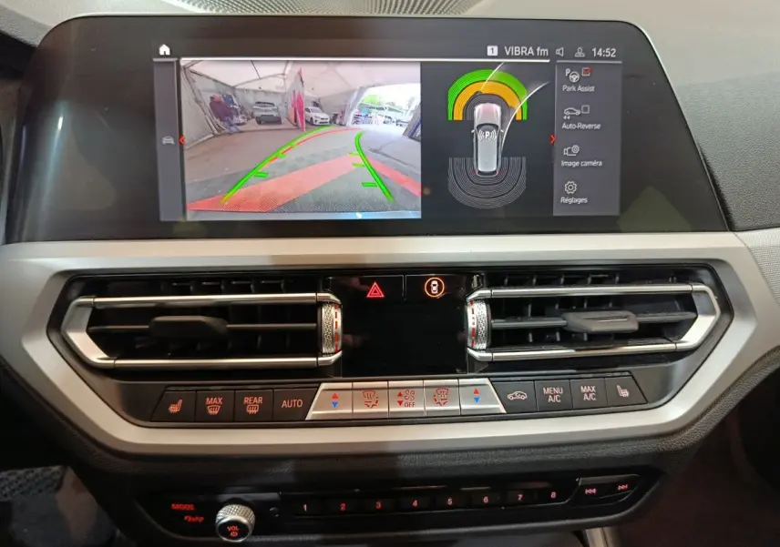 Écran tactile central avec affichage caméra de recul et commandes climatisation dans l'habitacle d'une BMW Série 3 gris clair 2022.