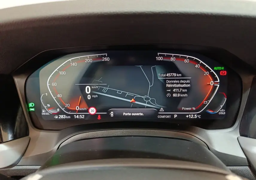 Tableau de bord numérique de BMW Série 3 316d 2022, affichage vitesse, navigation et alertes, vue frontale rapprochée.