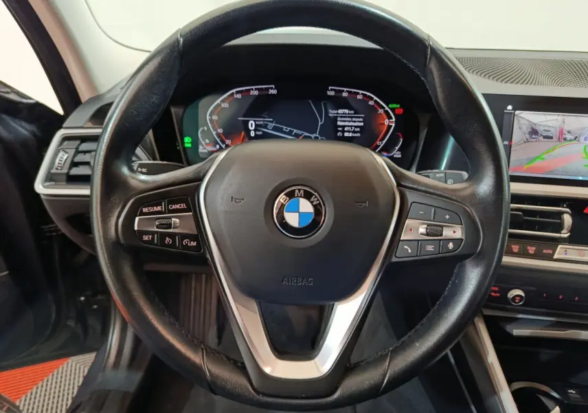 Vue rapprochée du volant cuir noir BMW Série 3 316d 2022 avec tableau de bord digital et écran tactile central.
