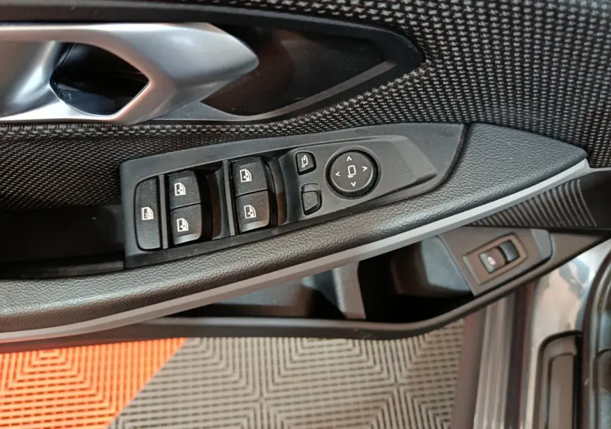 Vue rapprochée du panneau de commandes côté conducteur de la BMW Série 3 gris clair, avec boutons de vitres et rétroviseurs.