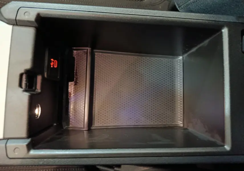 Vue rapprochée de la console centrale ouverte d'une BMW Série 3 gris clair, montrant un espace de rangement avec prise USB.