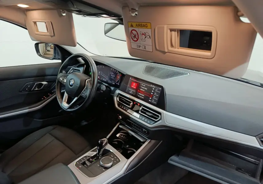 Intérieur BMW Série 3 316d 2022 vu côté conducteur, tableau de bord moderne avec écran tactile et volant cuir.