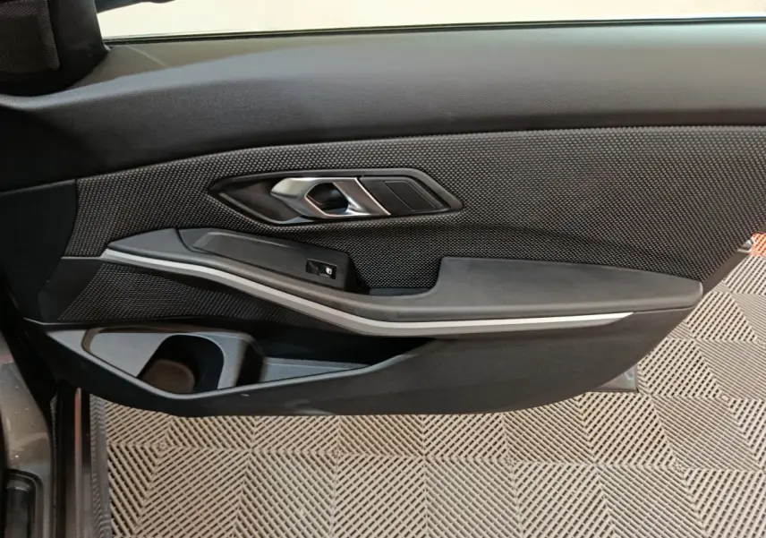 Gros plan sur la porte côté gauche de la BMW Série 3 316d 2022, avec garniture noire et insert argenté.