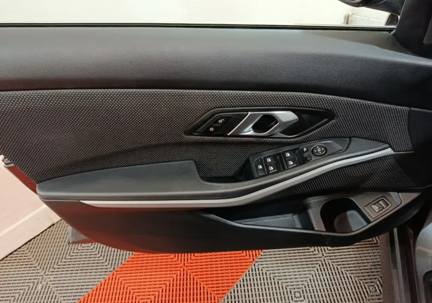 Détail de la porte côté gauche de la BMW Série 3 316d 2022 avec commandes de vitres et poignée argentée.