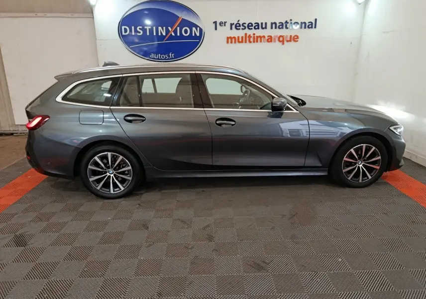 BMW Série 3 316d gris clair vue de profil côté gauche dans un showroom avec logo Distinxion en arrière-plan.