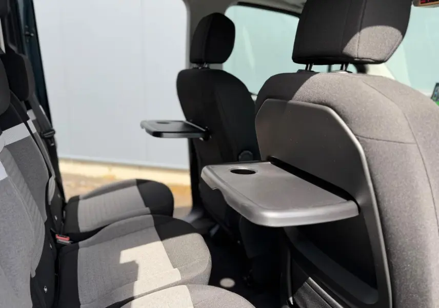 Vue latérale intérieure sur les sièges arrière gris et noirs du Citroën Berlingo Multispace avec tablette rabattable.