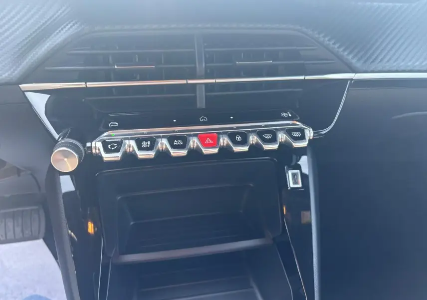 Vue rapprochée de la console centrale noire du Peugeot 2008 Hybrid 145 Style avec boutons de commande chromés.