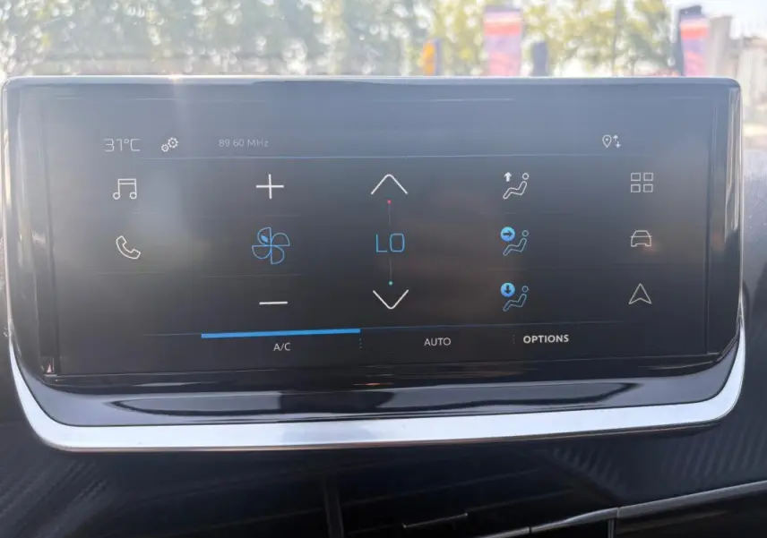 Écran tactile central du Peugeot 2008 Hybrid 145 Style 2025, affichant les commandes de climatisation en extérieur lumineux.