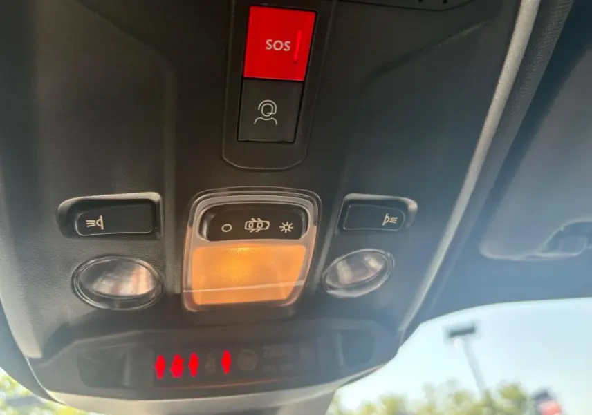 Vue en contre-plongée du plafonnier avant gris du Peugeot 2008 Hybrid 145 e-DCS6 Style 2025 avec bouton SOS rouge.