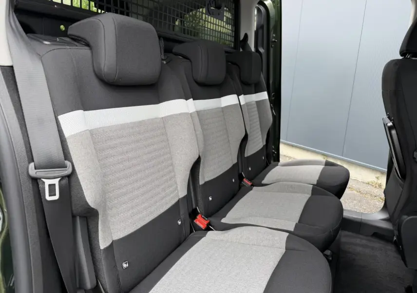 Vue latérale intérieure sur les trois sièges arrière gris et noirs du Citroën Berlingo Multispace Vert Sirkka avec porte coulissante ouverte.