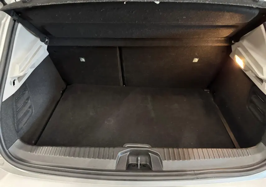 Coffre ouvert vu de l'arrière d'une Renault Clio V gris aluminium, montrant un espace de chargement propre et éclairé.