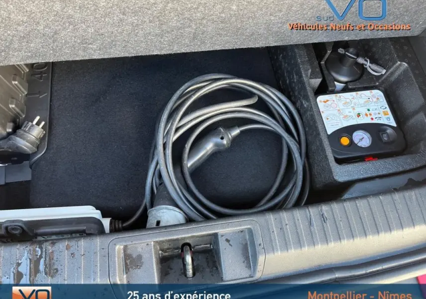 Coffre ouvert montrant le câble de recharge et kit de dépannage pneumatique du Renault Captur E-Tech Plug-in rouge.