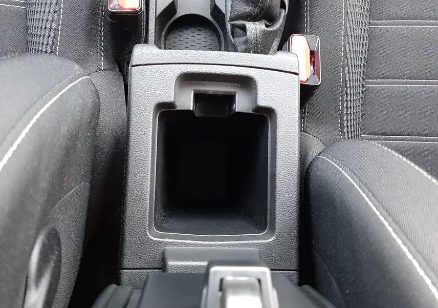 Vue plongeante sur la console centrale noire du Dacia Duster 2023, avec levier de vitesse manuel et porte-gobelets.