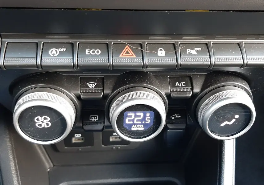 Gros plan sur la console centrale du Dacia Duster 2023, montrant les commandes de climatisation avec affichage digital à 22,5°C.