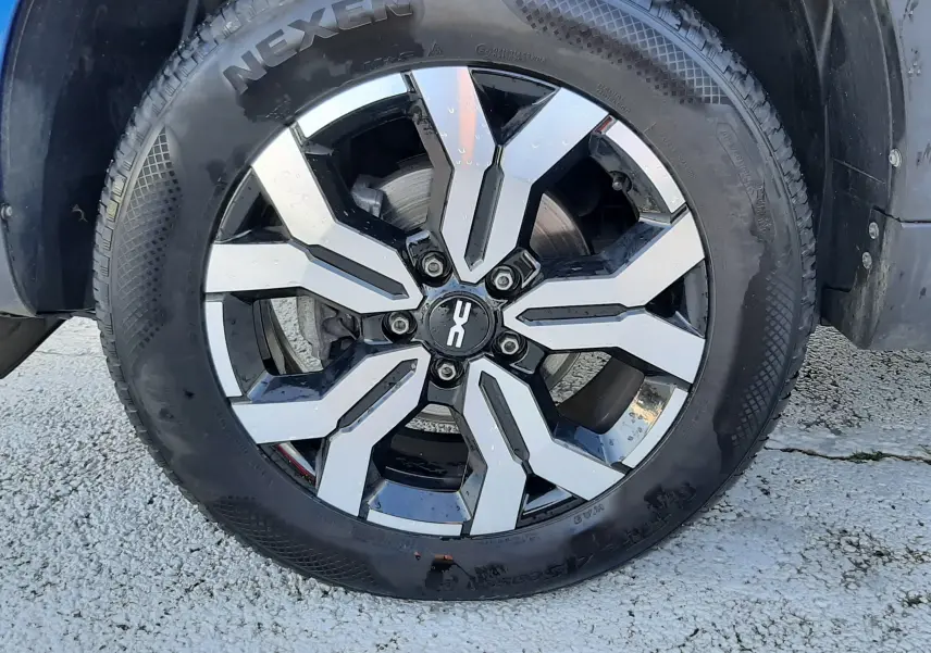 Vue rapprochée de l'arrière droit d'un Dacia Duster bleu 2023, montrant la roue et l'aile avec protection noire.