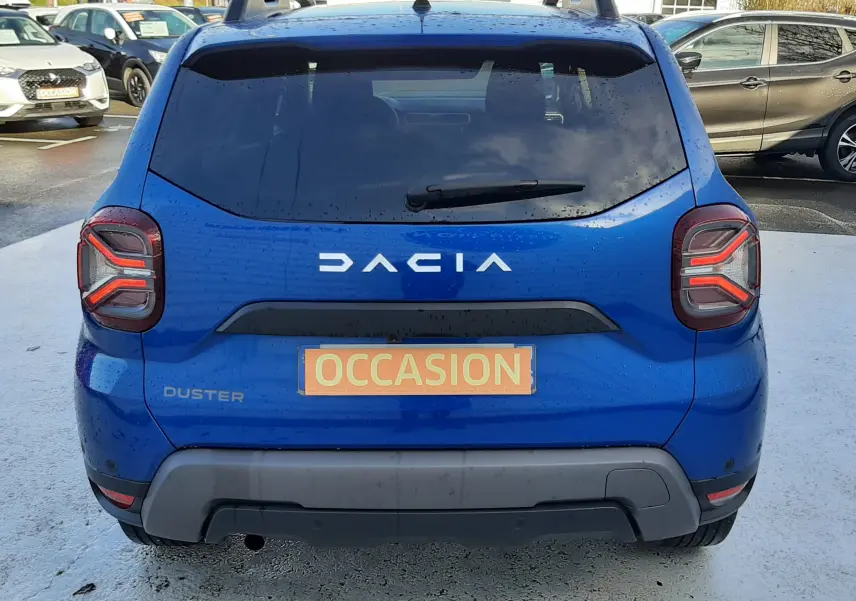 Vue arrière d'un Dacia Duster bleu 2023 avec feux arrière LED et plaque d'immatriculation "OCCASION".