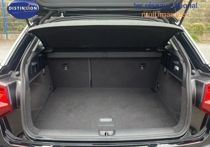 Coffre ouvert vu de l'arrière d'un Audi Q2 noir mito metal, montrant l'espace de chargement vide et les garnitures intérieures.