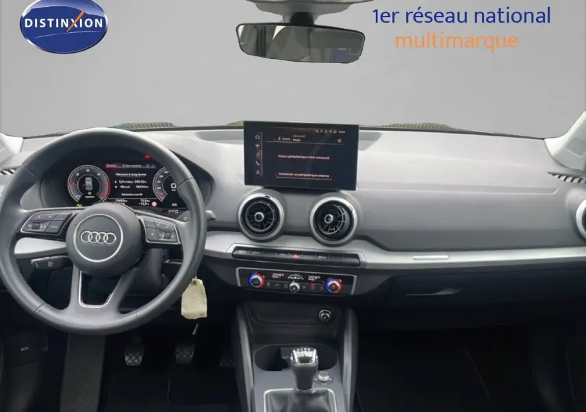 Vue avant de l'habitacle noir d'un Audi Q2 30 TDI S-Line 2025 avec tableau de bord numérique et écran central.