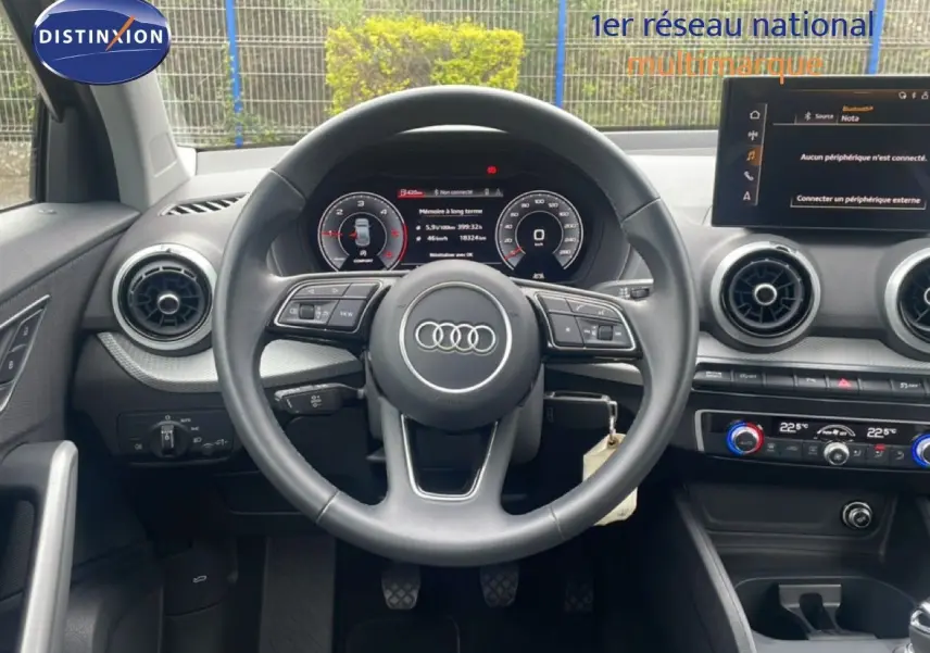 Vue intérieure centrée sur le volant Audi Q2 30 TDI S-Line 2025 avec tableau de bord numérique et commandes intégrées.