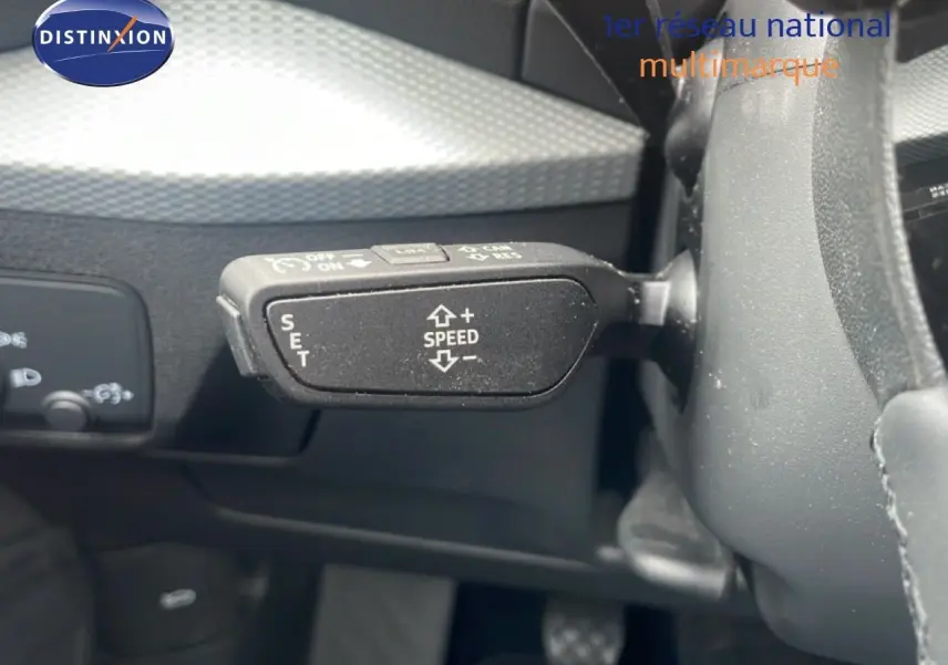 Gros plan sur la commande de régulateur de vitesse à gauche du volant dans l'habitacle noir de l'Audi Q2 30 TDI S-Line.