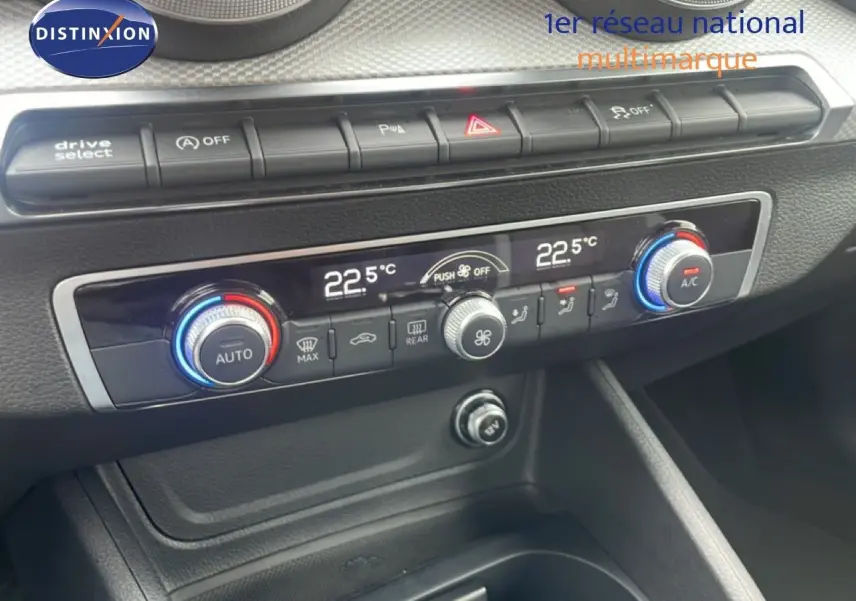 Vue rapprochée du tableau de bord de l'Audi Q2 30 TDI S-Line 2025, montrant les commandes de climatisation digitale et boutons fonctionnels.