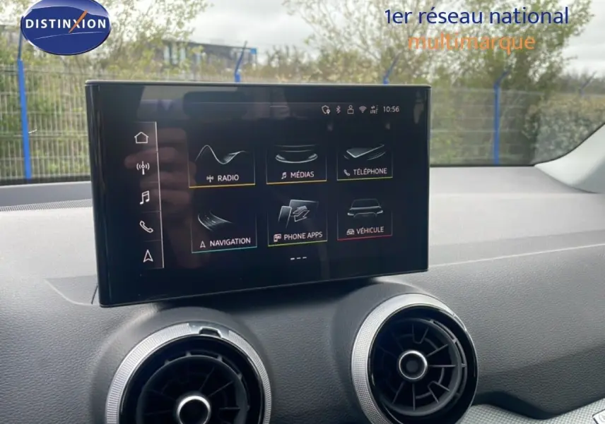 Écran tactile central avec interface multimédia, entouré de deux aérateurs ronds sur le tableau de bord d’un Audi Q2 noir.