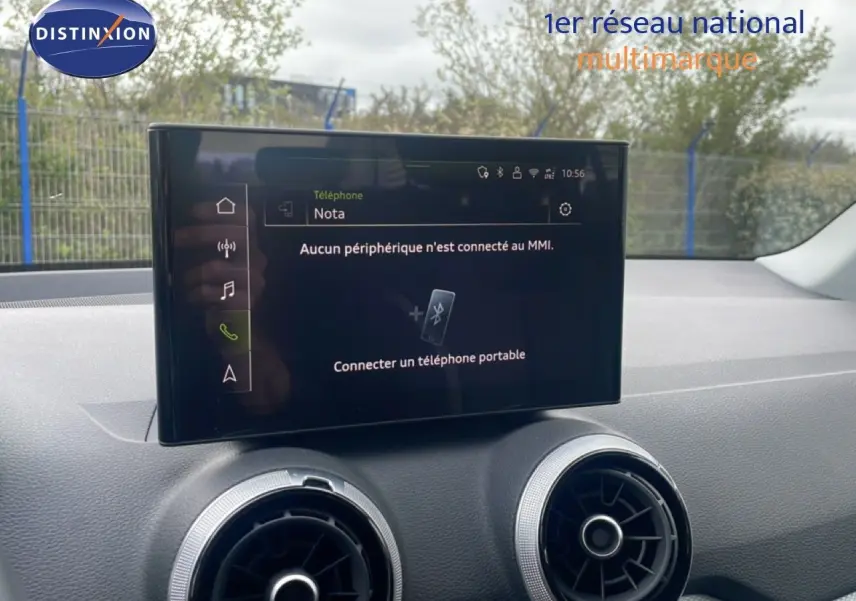 Écran tactile central avec interface MMI affichant la connexion Bluetooth, entouré de deux aérateurs ronds dans l’habitacle d’un Audi Q2 noir.