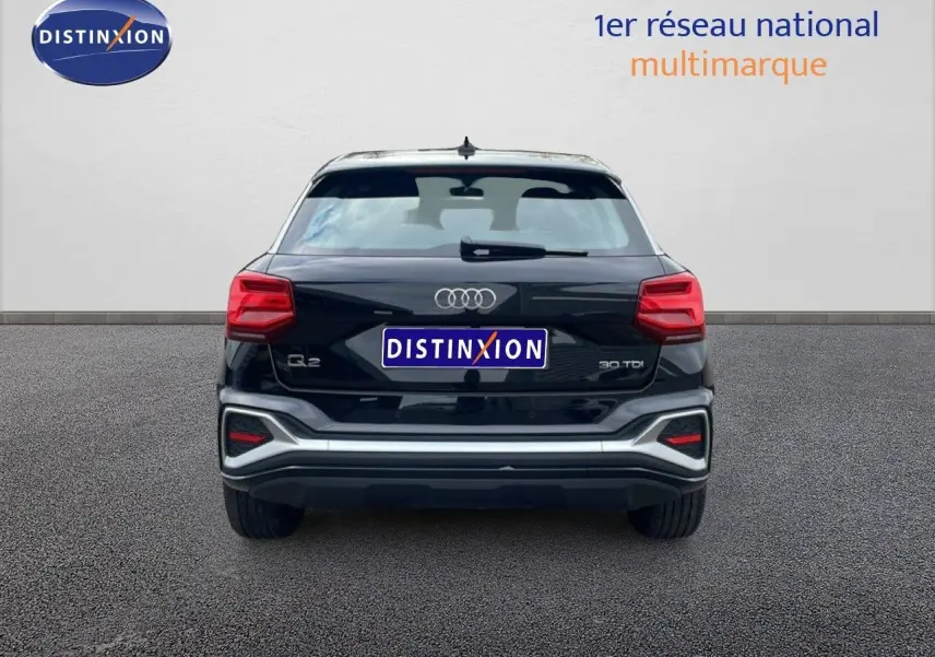 Vue arrière d’un Audi Q2 30 TDI S-Line noir mito metal avec feux rouges et détails argentés sur le pare-chocs.