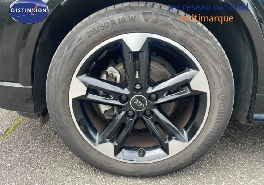 Gros plan sur la roue avant droite noire et argentée de l'Audi Q2 30 TDI S-Line 2025 avec logo Audi au centre.