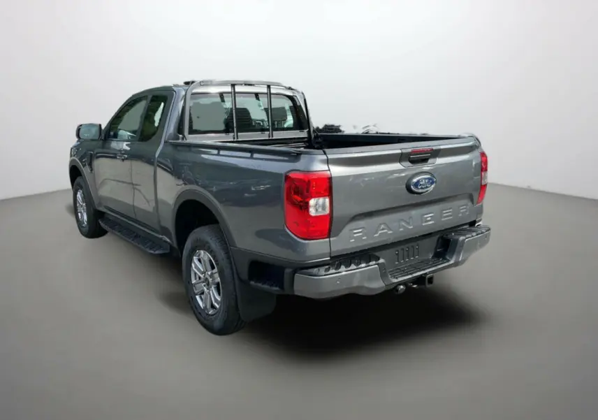 Vue 3/4 arrière du Ford Ranger gris carbone 2025 avec benne ouverte et barres de protection chromées.