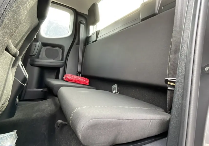 Vue intérieure arrière côté droit du Ford Ranger gris carbone, banquette simple avec ceinture de sécurité et trousse de secours rouge.