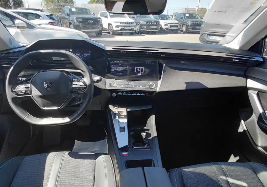 Vue intérieure avant de la Peugeot 308 gris, montrant le volant compact, le cockpit numérique et la console centrale moderne.